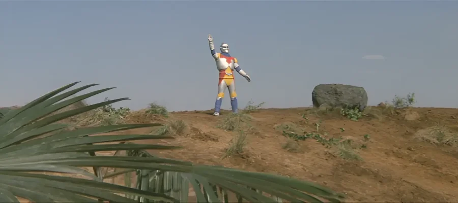 A screencap from the movie 'Godzilla vs Megalon' showing the robot Jet Jaguar waving at something offscreen.