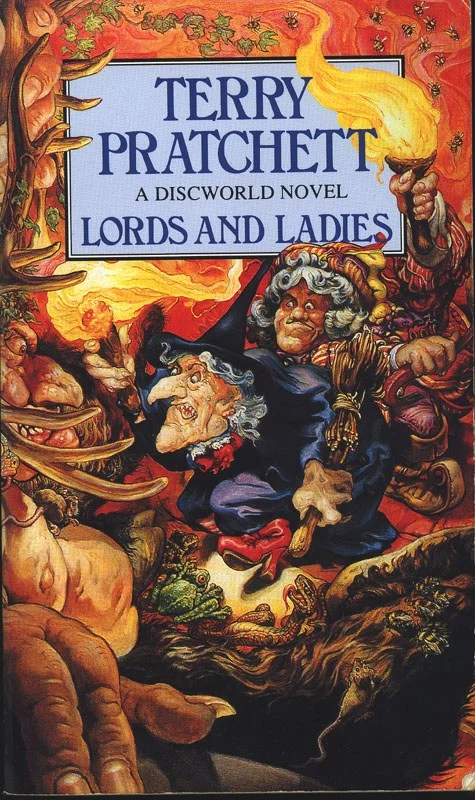 The original cover of the book Lords and Ladies. It shows a  witch holding up a torch in one hand and a broom in the other, while looming into the personal space of a tall, antlered giant of a humanoid. Behind her is a surprised looking indescribable person.